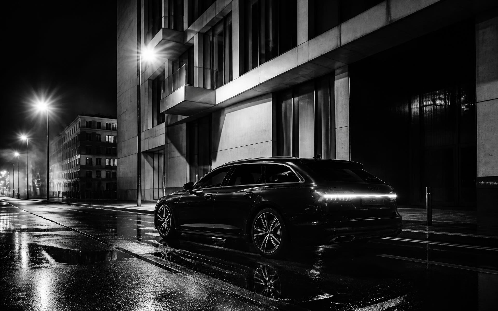 Dunkler Business-Kombi bei Nacht auf nasser Straße in Schwarzweiß